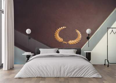 Black gift box detail with a golden laurel wreath icon Wall mural