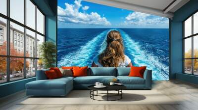 A woman with curly hair gazes at the vast blue ocean from a ship, capturing the ship's trailing wake under a sunny sky with scattered clouds, signifying freedom and adventure. Wall mural