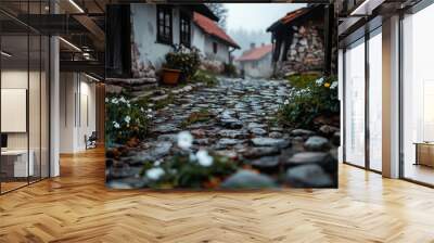 Misty village scene showcasing flowers and rustic stone houses lining a cobblestone path, highlighting the beauty of nature and tranquility in a quiet countryside setting. Wall mural