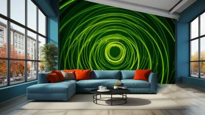 A beautiful, bright light swirl of green color. Futuristic light painting on a black background. Round light circles Wall mural