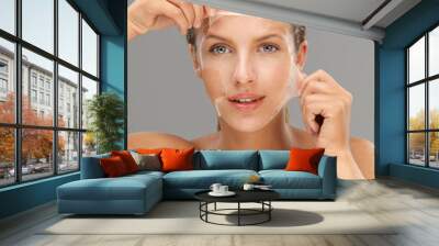 young woman taking off peeling mask Wall mural