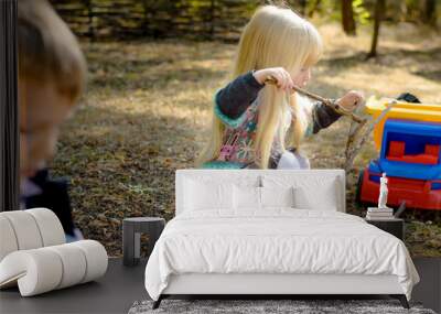 Little Blond Girl Playing Sticks on the Ground Wall mural