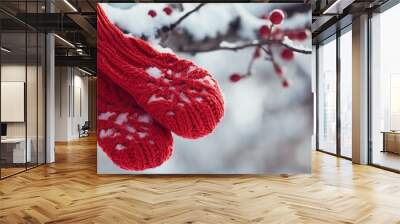 Knitted winter gloves hanging on a snowy tree branch, vibrant red color contrasted with white snow, cozy winter atmosphere Wall mural