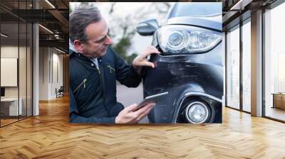 Auto Workshop Mechanic Inspecting Damage To Car And Filling In Repair Using Digital Tablet Wall mural