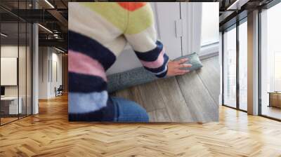 Close Up Of Woman Saving Enegy Insulating Home Putting Draught Excluder Against Front Door Wall mural