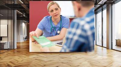 Female Doctor Discussing Leaflet With Male Patient Wall mural