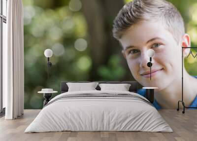 Portrait Of Happy Teenage Boy Sitting Outdoors Wall mural