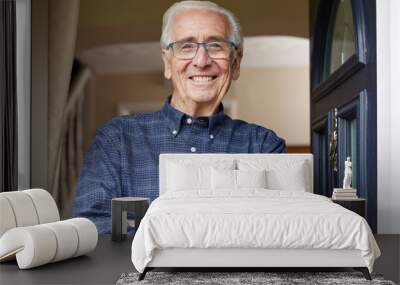 Portrait Of Smiling Senior Man Standing At Open Front Door Of House Wall mural