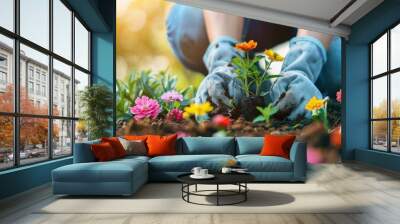 A gardener's hand gently planting vibrant flowers in the soil, symbolizing growth and care. Wall mural