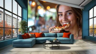 A young woman enjoying a delicious slice of pizza, smiling at a sunlit outdoor restaurant. Free copy space for text. Wall mural