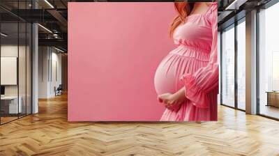 Close-up of a pregnant woman’s belly in a cozy pink sweater, against a soft pink background. Free copy space for banner. Wall mural