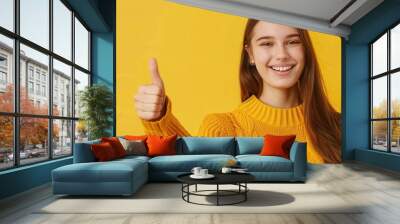 Smiling young woman in jacket, giving thumbs up. Free copy space for banner. Wall mural