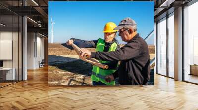 two engineers review blueprints in a windmill field. Wall mural