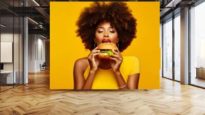 Afro woman eating a hamburger on a yellow background. Generative AI. Wall mural