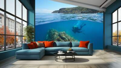 Mediterranean sea scuba diving, two divers underwater and rocky coastline in the Marine reserve of Cerbere Banyuls, split view over and under water surface, France, Occitanie, Pyrenees-Orientales Wall mural