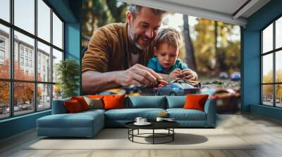 A father and son play with toy cars laid out on a table outdoors. Their expressions of joy and concentration highlight the bond and fun they are sharing together. Wall mural