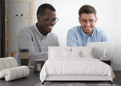 African guy pointing to data on laptop for his European colleague while working together on business project Wall mural