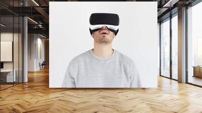 Amazed man experiencing virtual reality with VR headset, isolated on gray background Wall mural