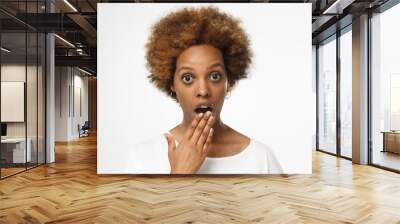 Close up photo of young african american woman isolated on gray background dressed in blank white t shirt, covering mouth with hand, experiencing deep astonishment Wall mural