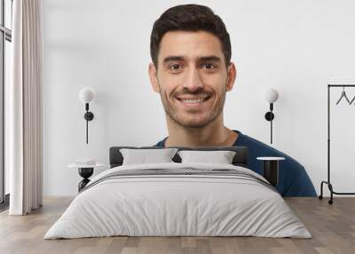 Close up portrait of smiling handsome guy in blue t-shirt isolated on gray background Wall mural