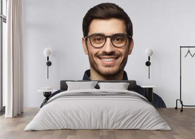 Close-up portrait of young man feeling happy and smiling, wearing denim shirt and stylish glasses, isolated on gray background Wall mural