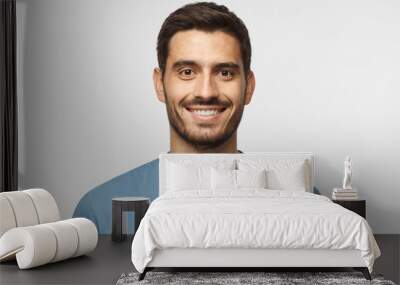 Close up portrait of young smiling handsome guy in blue t-shirt isolated on gray background Wall mural