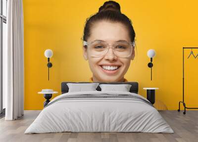 Close up shot of smiling attractive young woman isolated on yellow background Wall mural