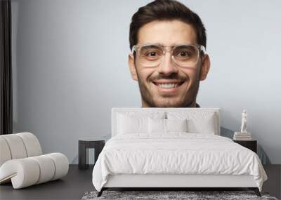 Closeup headshot of business man standing in blue shirt against gray background wearing transparent spectacles, smiling with satisfaction and confidence Wall mural