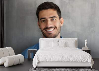 Closeup headshot of young handsome European Caucasian male isolated on grey background casting interested and bit cunning look to viewer, confident with his lifestyle and leisure time, smiling Wall mural