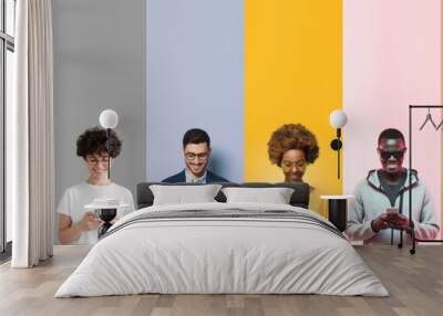 Group of smiling diverse people texting with phones, isolated on multicolored background Wall mural