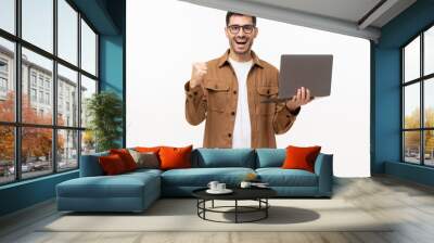 He's a winner! Happy young man in brown shirt looking at laptop screen with victory expression, isolated on gray background Wall mural