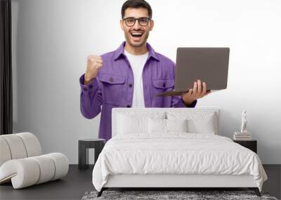 He's a winner! Happy young man in purple shirt looking at laptop screen with victory expression Wall mural