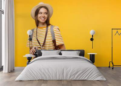 Horizontal banner of smiling young female tourist holding camera, isolated on yellow background with copy space Wall mural