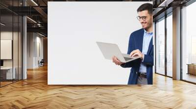 Horizontal banner of young handsome smiling business man holding laptop in hands, typing and browsing web pages, isolated on gray background with copy space Wall mural