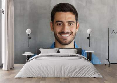 Indoor photo of handsome European guy pictured isolated on grey background standing close to camera with dark face hair and short haircut, looking satisfied and happy, spending his leisure time Wall mural