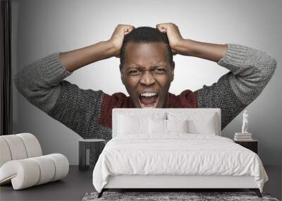 Mad African American man shouting with mouth wide open and closed eyes, holding hands on his head, trying to tear his hair out. Black male screaming with scared expression, yelling full of anger Wall mural