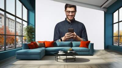 Man looking at phone, standing isolated on gray background Wall mural