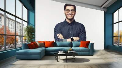 Man with crossed arms wearing glasses and smart watch, looking at camera with smile, standing isolated on gray Wall mural