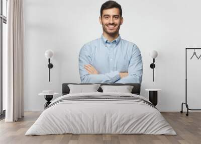 Modern business man in casual blue shirt standing with crossed arms, isolated on gray background Wall mural