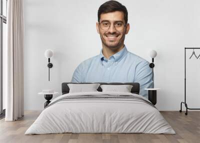 Modern businessman in blue shirt standing with crossed arms, isolated on gray background Wall mural