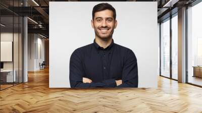 Modern cheerful business man in deep blue shirt standing with crossed arms, isolated on gray background Wall mural