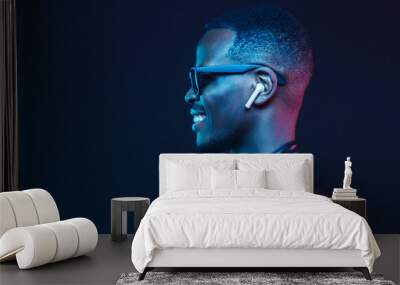 Neon portrait of smiling african man listening music with earphones, wearing black leather jacket Wall mural