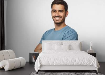 Portrait of attractive young sporty man in blue t-shirt standing with crossed arms isolated on gray background Wall mural