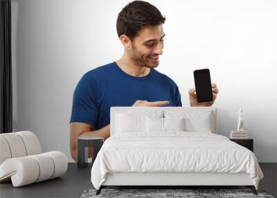 Portrait of happy man showing blank phone and pointing to black screen with finger Wall mural