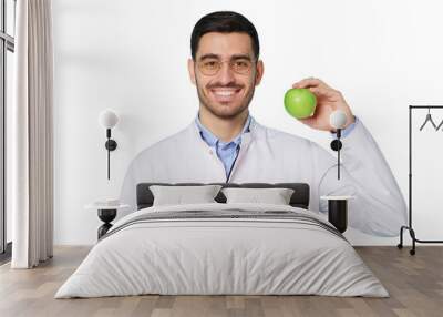 Portrait of smiling dentist or nutritionist doctor wearing white coat with fresh green apple in hand Wall mural