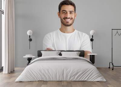 Portrait of smiling handsome man in white t-shirt, standing with crossed arms Wall mural