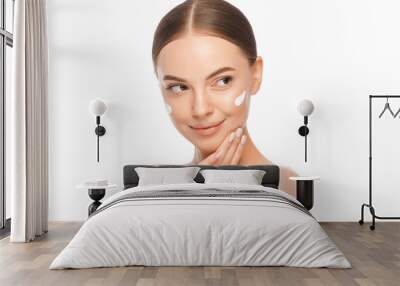 Portrait of young beautiful brown-eyed woman with face cream on cheekbones, skin care concept Wall mural