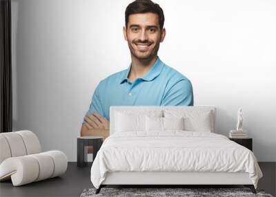 Portrait of young european man standing in blue polo shirt with crossed arms, smiling and  looking at camera Wall mural