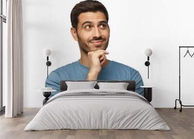 Portrait of young man in blue t-shirt with dreamy cheerful expression, thinking, isolated Wall mural