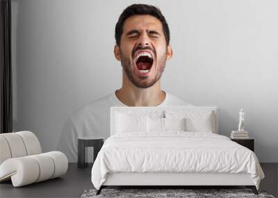 Screaming with closed eyes crazy young man in blank white t-shirt isolated on gray background Wall mural